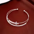 Vista dettagliata dell'elegante bracciale rigido a doppio strato con croce di zirconi - Zircone bianco / Argento