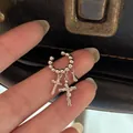 Nahaufnahme einer silbernen Perlen-Ohrmanschette mit Kreuz- und Tropfenanhängern. - Einzelstück / Silber