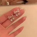 Gros plan montrant le design délicat du nœud avec perles et zircons cœur. - Argent-Blanc