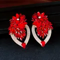 Gedetailleerde weergave van rode bloemkristallen oorbellen met strass-accenten op zwart - Goud-Rood