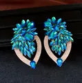 Gedetailleerd overzicht van oversized groenblauwe kristallen bloemoorbellen met strass. - Goud-Blauw
