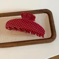 Detailopname van een rode acryl haarklem met witte stippen op een houten dienblad - Stippenstijl / Rood