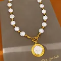 Close-up view of a vintage wrinkled pearl necklace with a gold portrait coin pendant. - Wrinkled Pearl Portrait Pendant Necklace / Gold-White