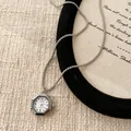 Vue macro d'un pendentif montre à quartz hexagonal argenté sur une chaîne fine - Polygone / Argent