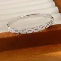 Gedetailleerde close-up van een zilverkleurige armband met schakels en glimmende zirkonia. - Zilver