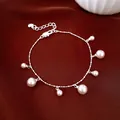 Detailed shot of a silver chain bracelet featuring dangling white pearls on luxury red silk background. - Silver-Pink