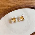 Detailopname van elegante Franse stijl bloem pareloorbellen met gouden bloemblaadjes. - Franse Bloemen Parel Oorknopjes (Zilveren Stift) / Goud/Wit
