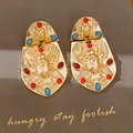 Detaillierte Nahaufnahme von Vintage-Gold-Skarabäus-Ohrringen mit rot-blauen Edelsteinen - Gold mit rot-blauem Inlay