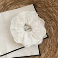 Detail van een elegante gebroken witte kanten scrunchie met fijn bloemenborduurwerk - Beige Geborduurde Kant Stijl