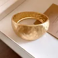 Detailed macro shot of a chunky gold hammered textured hinged bangle with elegant matte finish - Gold-Matte-Round