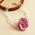 Close-up detail of vintage pink fabric rose and multi-layered white pearl strand necklace - Pink