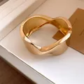 Close-up of gold wavy irregular cuff bracelet with a smooth and shiny metallic finish - Shiny Gold