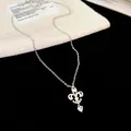 Gros plan détaillé du collier fleur de lys avec un pendentif en zircon étincelant en cœur - Argent