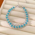 Gros plan d'un bracelet en maille d'argent ajustable avec des perles de verre bleues. - Bleu