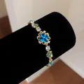 Detailed close-up shot of ice blue zircon flower gold bracelet on black velvet display - Style 1