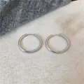 Close-up of minimalist silver circular hoop earrings with rhinestone micro-pave details - Silver