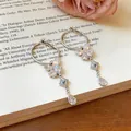 Detailopname van sprankelende zirkonia vlinder oorbellen met elegante waterdruppel kwastjes - Zilveren oorknopjes stijl / Zilver