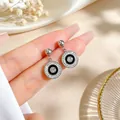 Close-up of minimalist titanium steel round earrings with crystals and black enamel. - Steel Color Earrings
