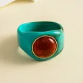 Makrodetail eines marmorierten Acryl-Armbands mit großem zentralem bernsteinfarbenem Harzstein - Cyan-Orange