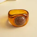 Detailansicht eines vintage bernsteinfarbenen Acryl-Armreifs mit rundem Harz-Inlay - Braun und Rosa