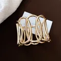 Detailansicht eines goldfarbenen hohlen ovalen offenen Armreifs für modebewusste Damen. - Gold
