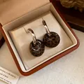 Detailansicht von Retro-Ohrringen mit Leopardenmuster und Silbernadeln in einer Schmuckschatulle - Silberstift - Silber - Kaffee - Rund