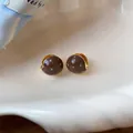 Detailed macro view of Maillard brown polka dot enamel earrings on a creamy seashell - Clasp Back / Brown