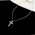 Primer plano de un collar con colgante de cruz de circón sobre fondo de terciopelo negro. - 1 Pieza / Plata-Blanco
