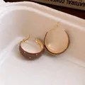 Detailed close-up of retro brown enamel hoop earrings featuring elegant white polka dots. - Coffee Polka Dot / Gold