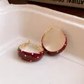 Macro view of vintage red enamel hoop earrings with a classic white polka dot pattern - Red Polka Dot / Gold