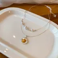 Nahaufnahme einer zweilagigen Silberhalskette mit Perlen und einem Gänseblümchen-Anhänger - Doppelschicht Gänseblümchen Stil / Silber und Goldton