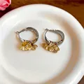Primo piano di orecchini a cerchio vintage con fascia argento e dettagli floreali dorati. - Stile Cerchio Dorato / Oro/Argento