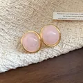 Close-up detail of vintage pink resin oval stud earrings with elegant gold-tone rim - Pink