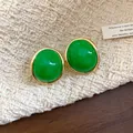 Close-up detail of retro green resin oval stud earrings with elegant gold-tone borders - Green