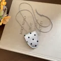Vue détaillée d'un collier porte-lunettes vintage à pois argentés sur un livre en lin. - Argent