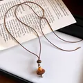 Détail macro du pendentif champignon vintage avec motif léopard sur cordon en cuir brun - Champignon / Marron