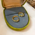 Detail van gouden oorringen met groene bloemen in een luxe groen fluwelen doosje - Zirconia Ring Stijl