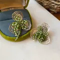 Detailopname van bosgroene kristallen bloemenoorknopjes met filigraan gouden blaadjes. - Holle Mesh Bloem Stijl