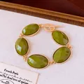 Detail van een luxe armband met olijfgroene gefacetteerde ovale stenen van hars. - Groen