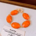 Close-up van een oranje ovale hars armband met een elegante goudkleurige OT-sluiting - Oranje