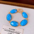Detailopname van vintage gouden armband met gefacetteerde ovale blauwe hars en T-sluiting - Blauw