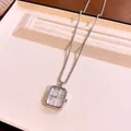 Dettaglio di un ciondolo orologio quadrato in argento su una catena in un vassoio. - Rettangolo / Argento