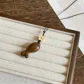Gedetailleerd zicht op een houten eikel hanger ketting in Zen-stijl op een luxe sieradenbord. - Eikel vorm