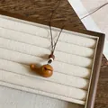 Close-up van een handgemaakte houten walvis hanger ketting op een sieraden display. - Walvisvorm