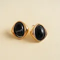 Makroansicht von Vintage-Ohrringen mit marmoriertem schwarzem Acryl und Gold - Dunkelblau