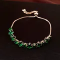 Vue détaillée d'un bracelet doré ajustable orné de zircons ovales vert émeraude - Or-Vert