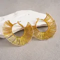 Détail rapproché de créoles tressées dorées avec un design géométrique ajouré élégant - Or