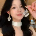 Close-up view of model wearing sparkling vintage palace style diamond drop earrings - Waterdrop Rhombus Drop Stud Earrings (HE35703-1) / Gold, White
