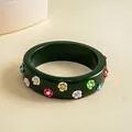 Detailed view of a dark green resin bangle featuring small colorful 3D flower accents. - Green