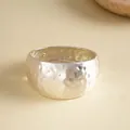 Close-up of a wide silver-finished bangle featuring a unique hammered and wrinkled metal texture - Brushed Silver Style